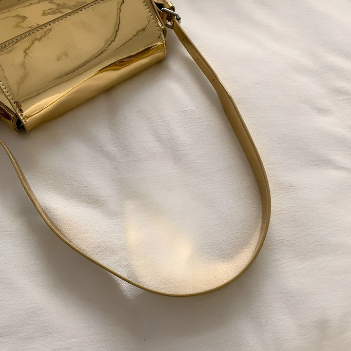 Détail d'un sac à main doré brillant avec anse en cuir beige, 46194032705760