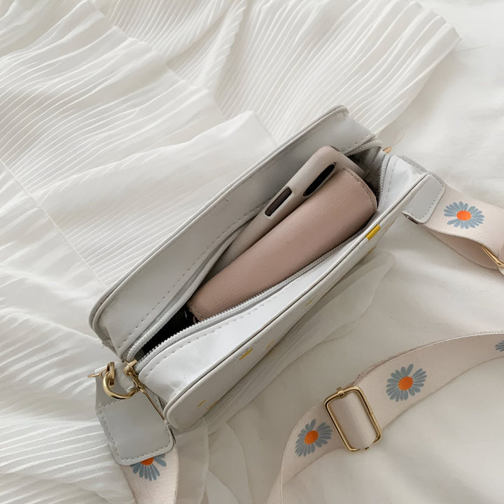 Sac blanc ouvert contenant un téléphone, avec sangle à motif marguerite., 46193876795616,46193876828384,46193876861152,46193876893920