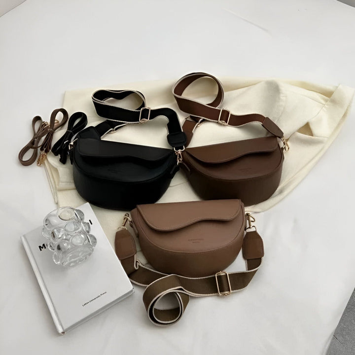 Trois sacs bandoulière noirs, marron et taupe avec large bretelle réglable, posés sur un drap blanc., 46194067079392,46194067112160,46194067144928