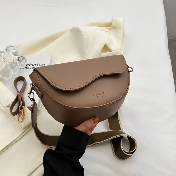 Sac bandoulière marron de forme demi-lune, tenu par une main., 46194067079392,46194067112160,46194067144928