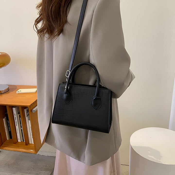 Sac à main noir texturé crocodile avec bandoulière, porté par une femme., 46194066030816,46194066063584