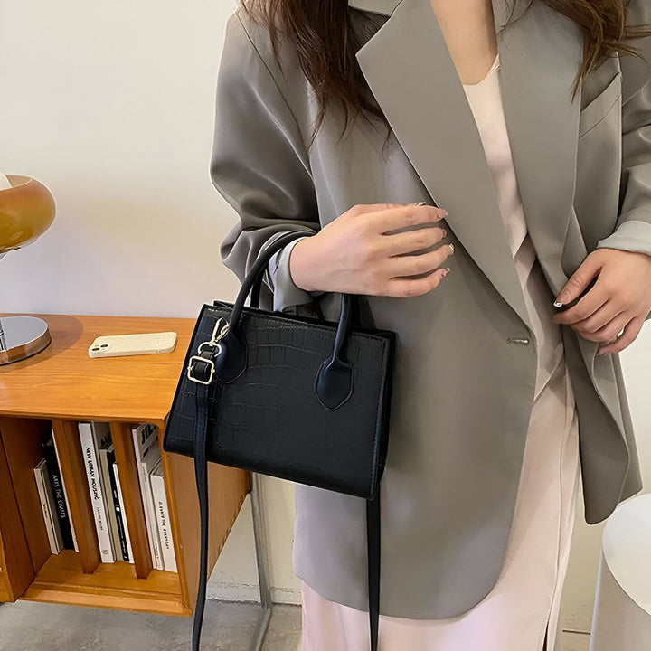 Sac à main noir motif crocodile porté par une personne en blazer gris, 46194066030816,46194066063584
