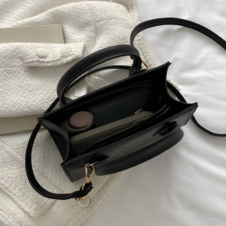 Sac à main noir ouvert avec téléphone, bouteille et portefeuille à l'intérieur, sur tissu blanc., 46194066030816,46194066063584