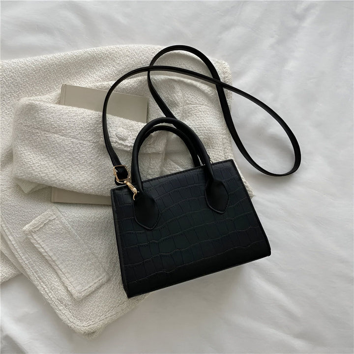 Sac à main noir effet crocodile avec anse courte et longue bandoulière sur fond blanc texturé., 46194066030816,46194066063584