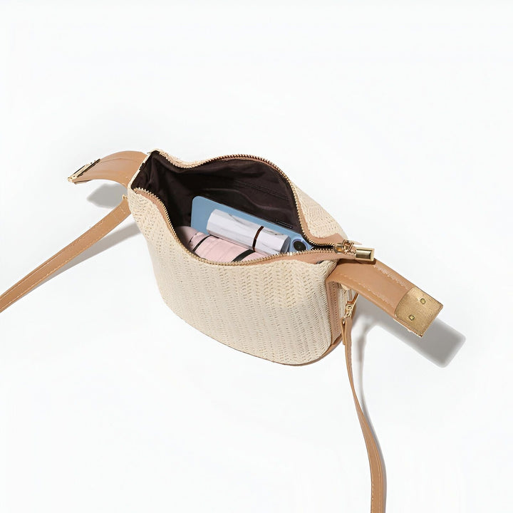 Sac à bandoulière en paille beige ouvert montrant un téléphone, une étole rose et un accessoire blanc., 46194030674144