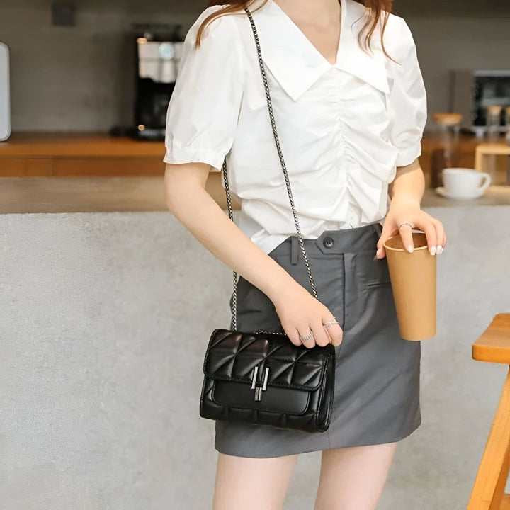 Femme avec petit sac bandoulière noir matelassé et chaîne argentée, tenant une boisson., 46193948950752,46193948983520