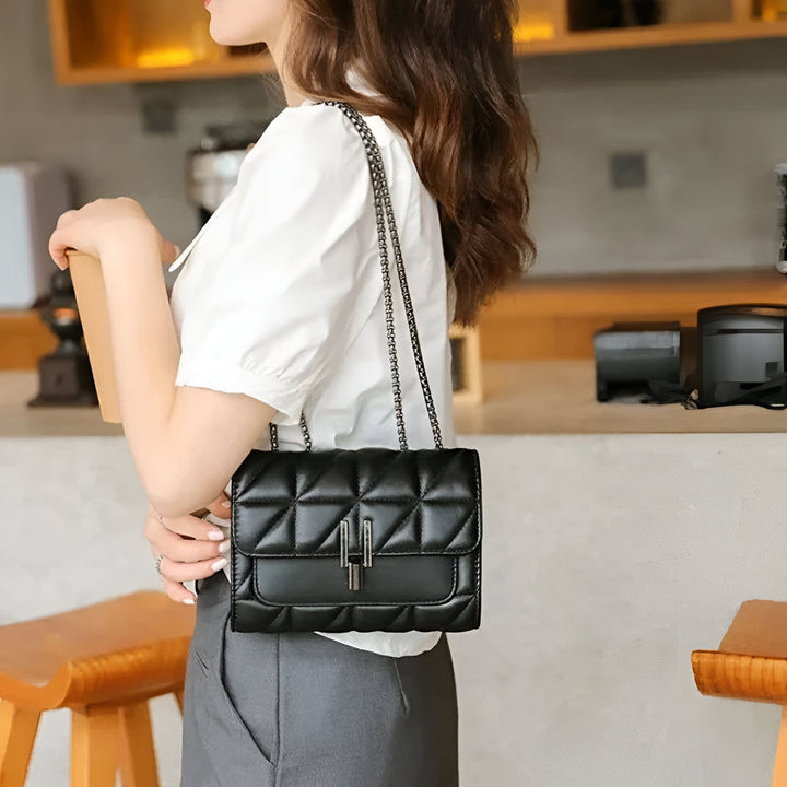 Femme portant un sac à main noir matelassé avec chaîne., 46193948950752,46193948983520
