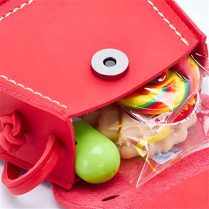 Contenu d'un sac rouge : une sucette arc-en-ciel, un biscuit et un objet vert., 46193988698336,46193988731104,46193988796640,46193988829408,46193988862176,46193988894944,46193988927712