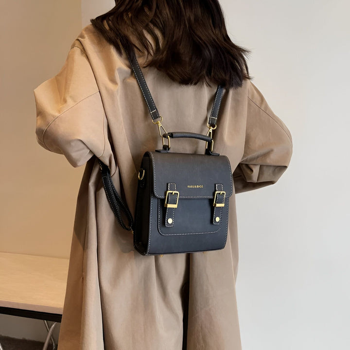 Personne de dos en manteau marron clair, portant un petit sac à dos noir à boucles dorées., 46193901863136,46193901895904,46193901928672