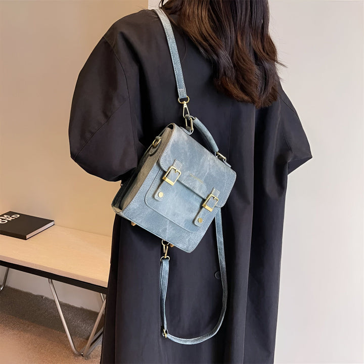 Sac cartable bleu gris à boucles dorées, porté en bandoulière par une femme en manteau noir, 46193901863136,46193901895904,46193901928672