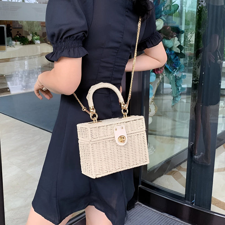 Sac à main rectangulaire en paille beige porté par une femme en robe noire., 46193945215200,46193945247968,46193945280736