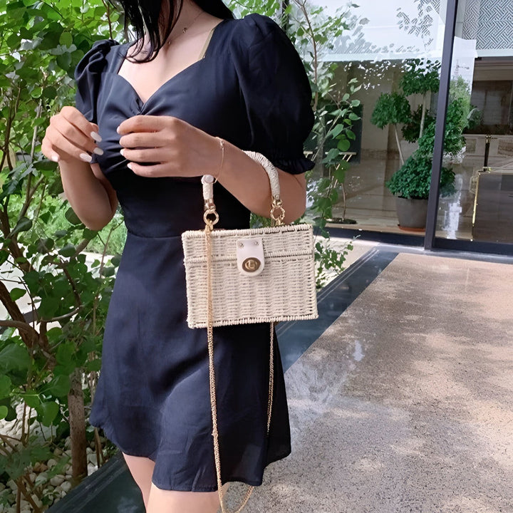 Femme en robe noire avec sac en paille blanc, anse et chaîne dorées., 46193945215200,46193945247968,46193945280736