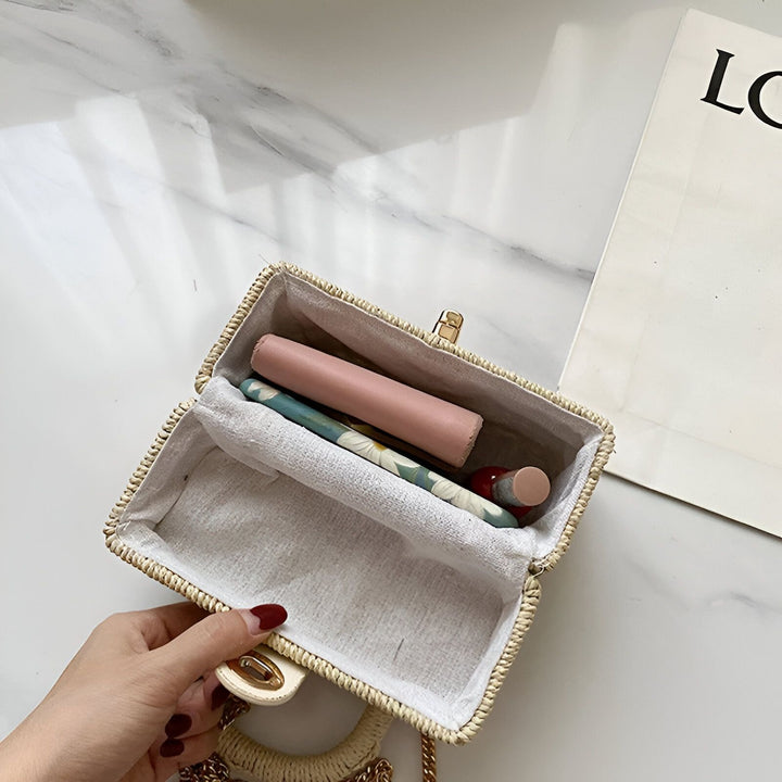 Main ouvrant une petite sacoche en paille contenant des produits de beauté., 46193945215200,46193945247968,46193945280736