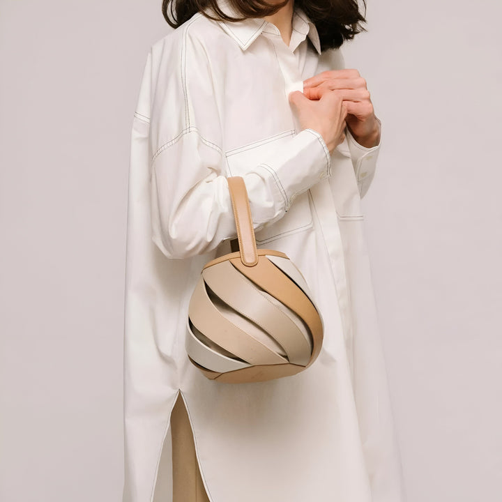 Femme en chemise blanche tenant un sac à main beige, blanc et marron au design tressé unique., 46193872994528,46193873027296,46193873060064,46193873092832