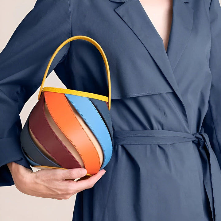 Sac à main en cuir multicolore au design unique, tenu avec un manteau bleu marine., 46193872994528,46193873027296,46193873060064,46193873092832