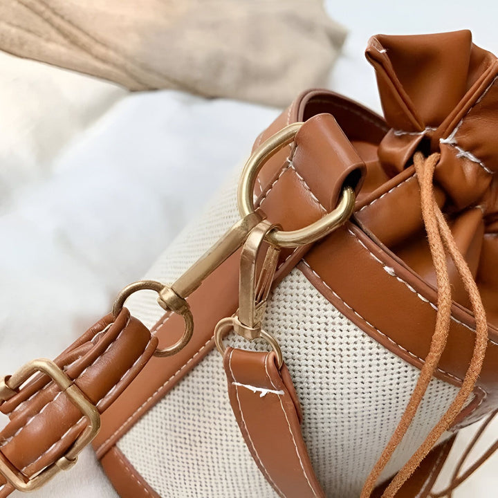 Détail d'un sac seau beige en toile et cuir marron avec fermoir cordon et boucles dorées., 46194011308256,46194011373792