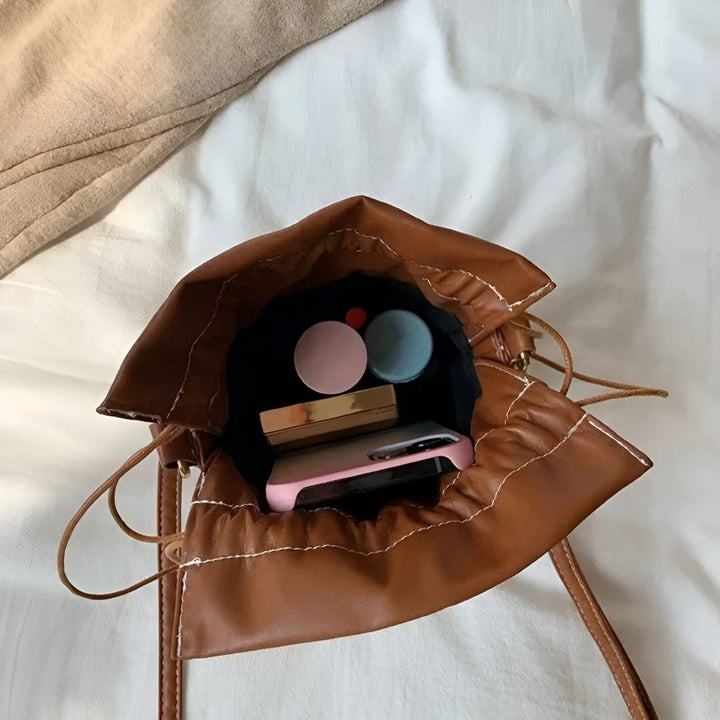Sac bourse en cuir marron vu de dessus contenant maquillage et téléphone portable., 46194011308256,46194011373792