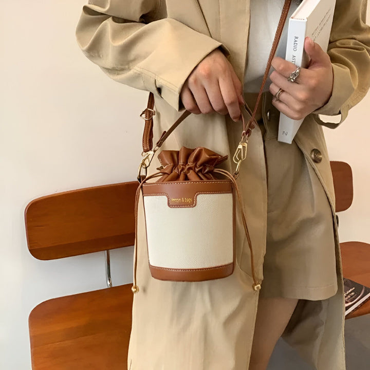 Gros plan sur un sac seau blanc et marron porté avec un manteau beige., 46194011308256,46194011373792