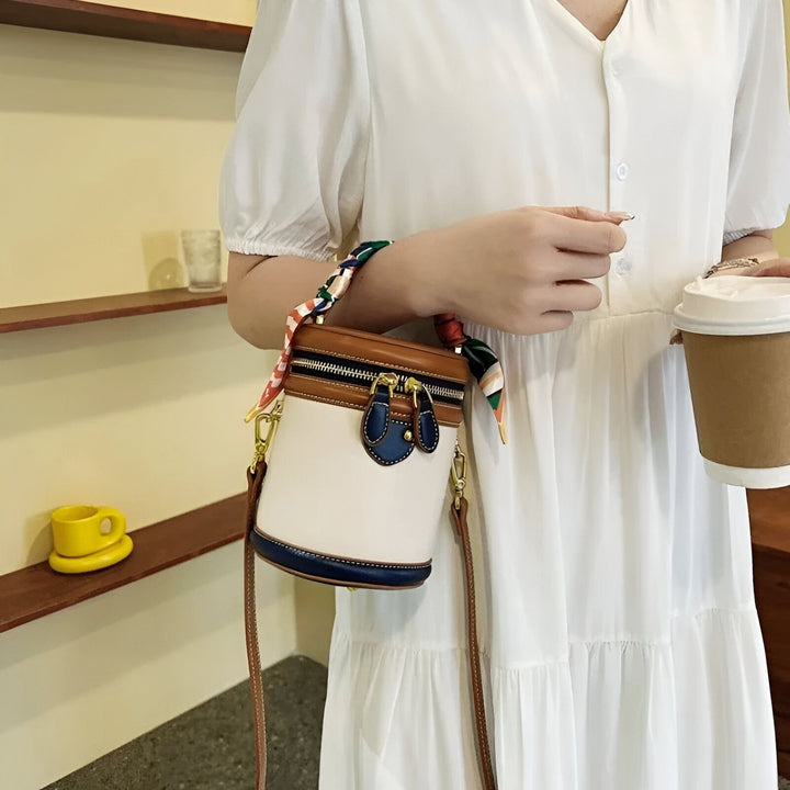 Sac à main cylindrique blanc, marron et bleu avec poignée foulard, tenu par une femme avec un café., 46194010128608