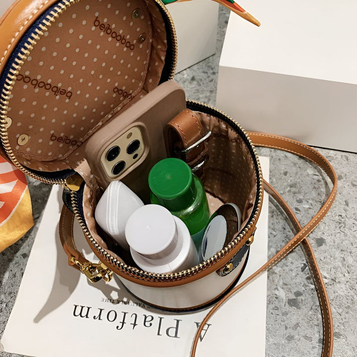 Contenu d'un petit sac à main rond ouvert : téléphone, flacons et accessoires., 46194010128608