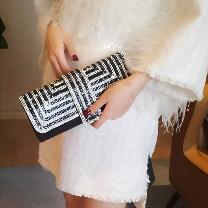 Pochette noire et argent avec perles et motifs géométriques, tenue par une personne., 46194019074272