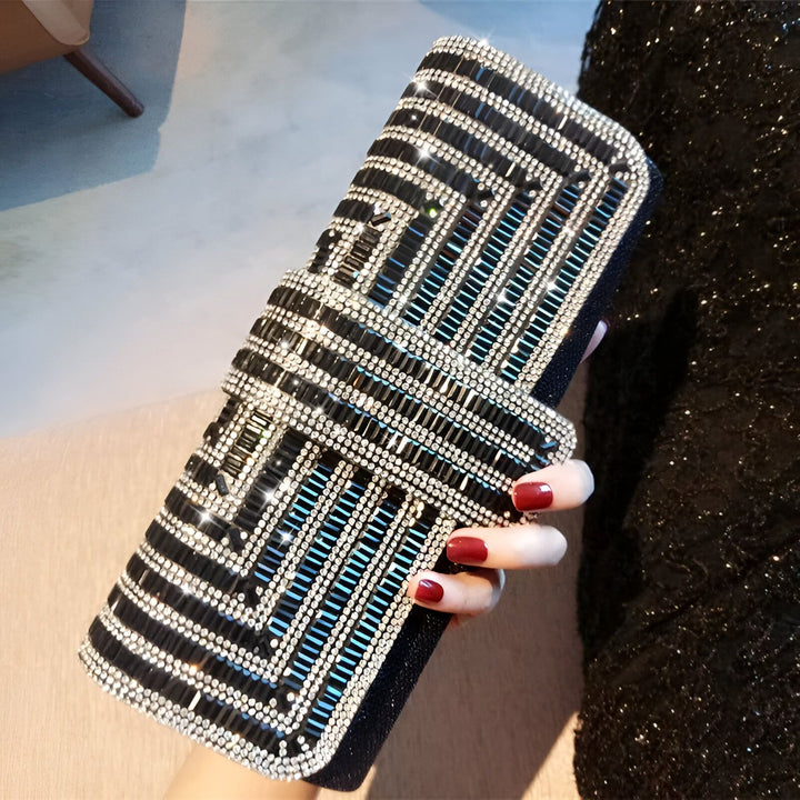 Pochette noire ornée de strass géométriques tenue par une main manucurée rouge, 46194019074272
