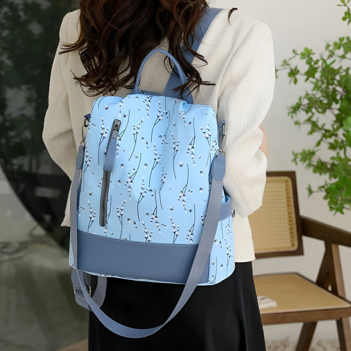 Sac à dos bleu clair avec motif floral blanc et base bleue foncée., 46193997971680,46193998004448,46193998037216,46193998069984