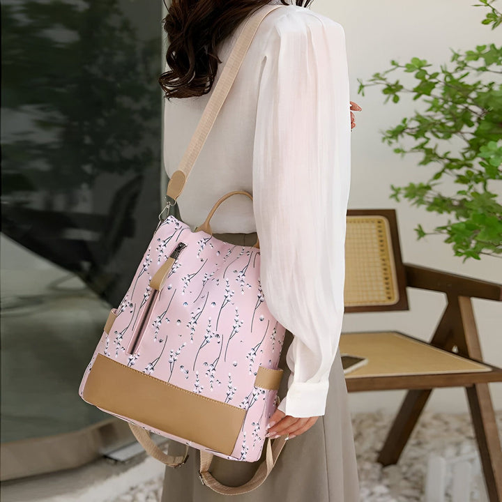 Sac à dos rose fleuri avec détails marron porté par une femme., 46193997971680,46193998004448,46193998037216,46193998069984