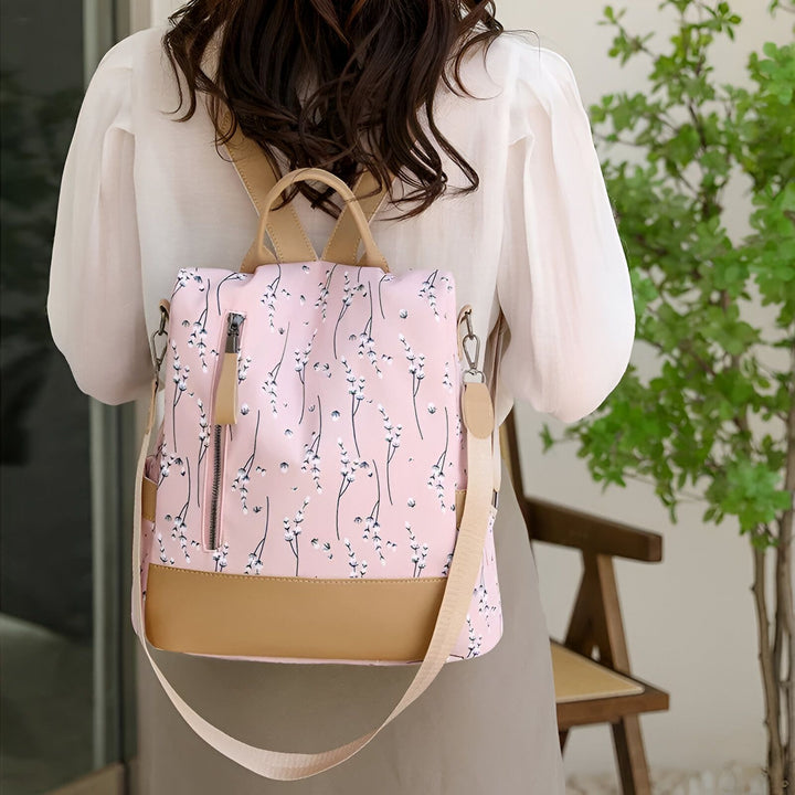 Sac à dos rose avec motif floral blanc et détails marron clair, porté par une femme., 46193997971680,46193998004448,46193998037216,46193998069984