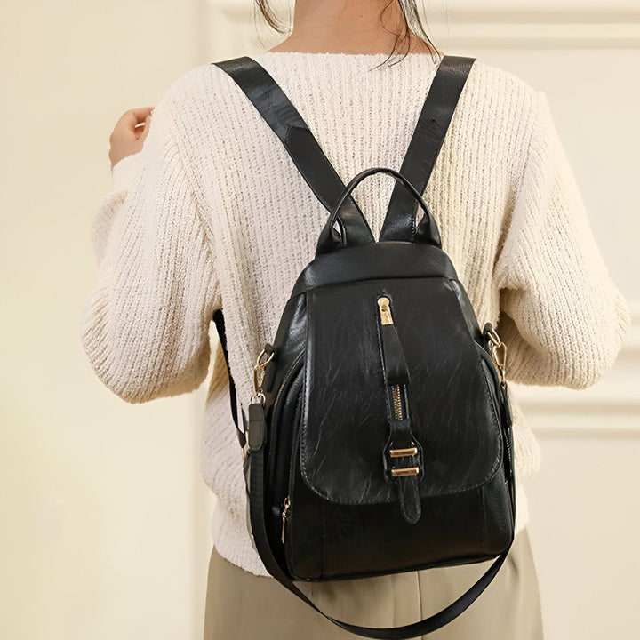 Femme de dos portant un sac à dos noir en cuir sur un pull crème., 46193999642848,46193999675616,46193999708384