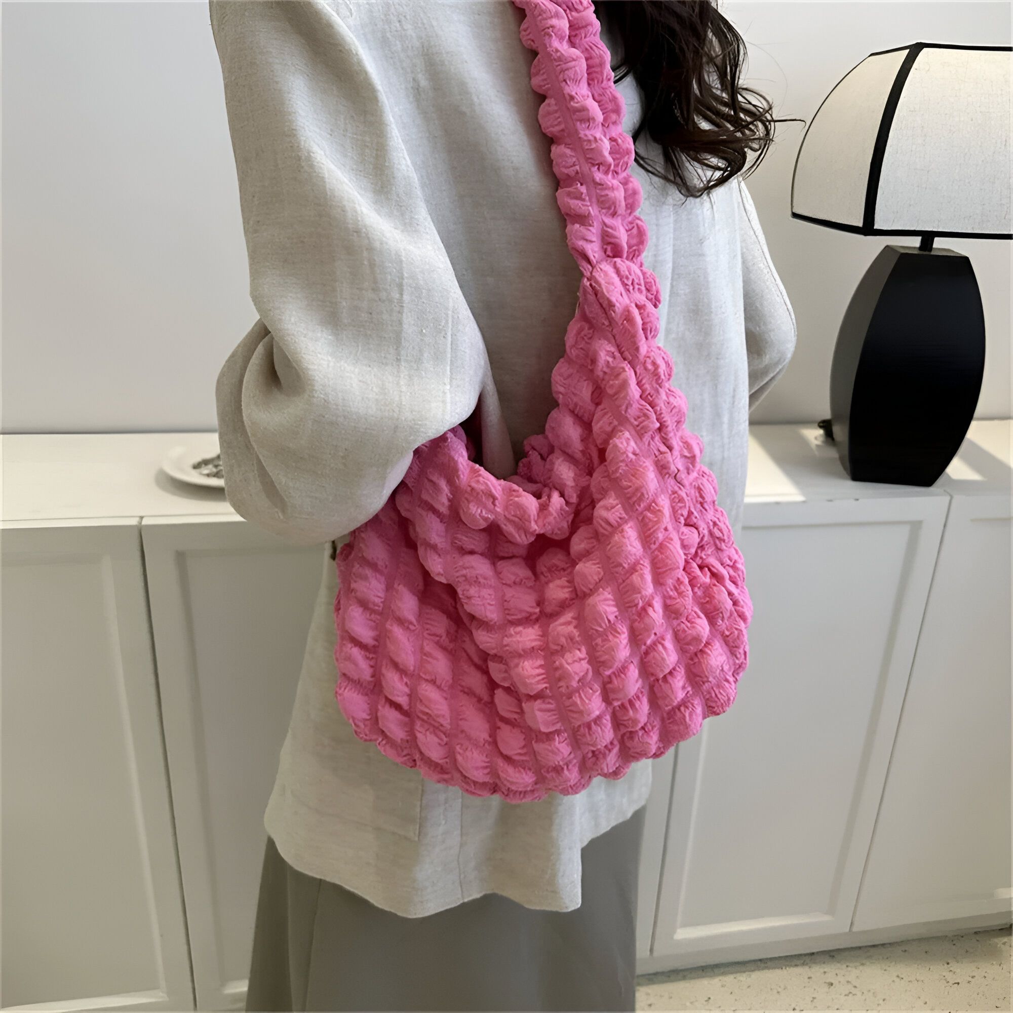 Une femme portant un sac à main rose en tissu bouclé.