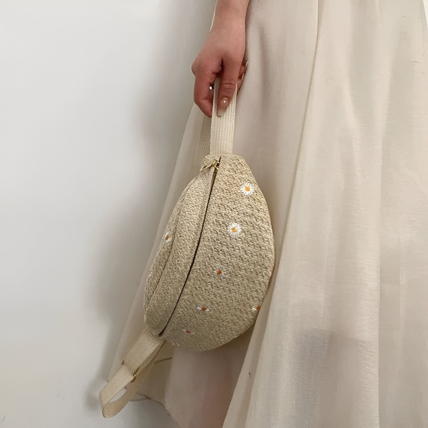 Sac banane en paille beige avec des marguerites brodées.