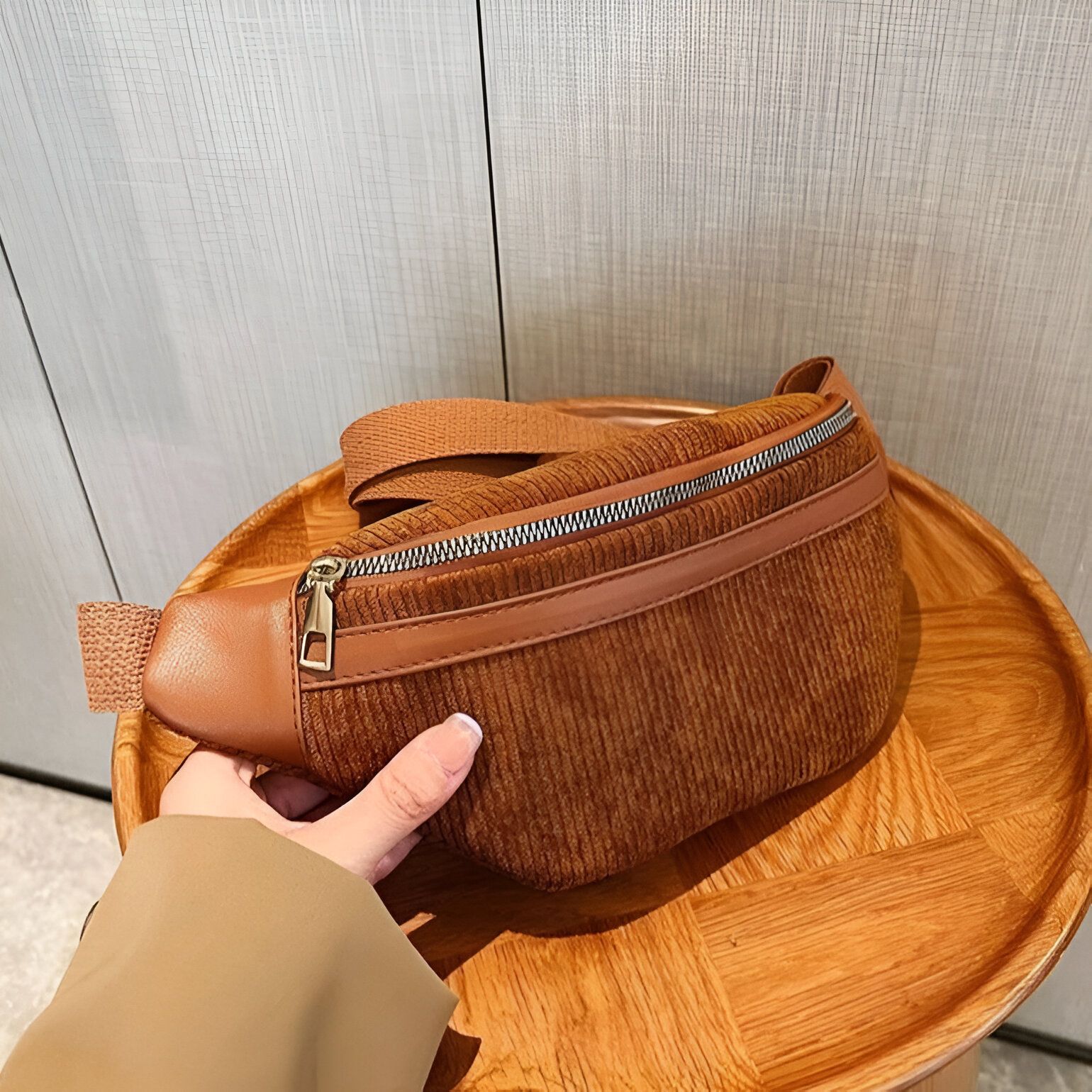 Un sac banane en velours côtelé marron sur un fond en bois.