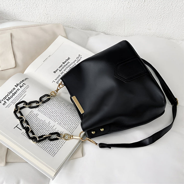Sac à main noir avec double anse chaîne épaisse et bandoulière fine posé sur un livre ouvert., 46193874272480,46193874305248,46193874338016,46193874370784,46193874403552,46193874436320
