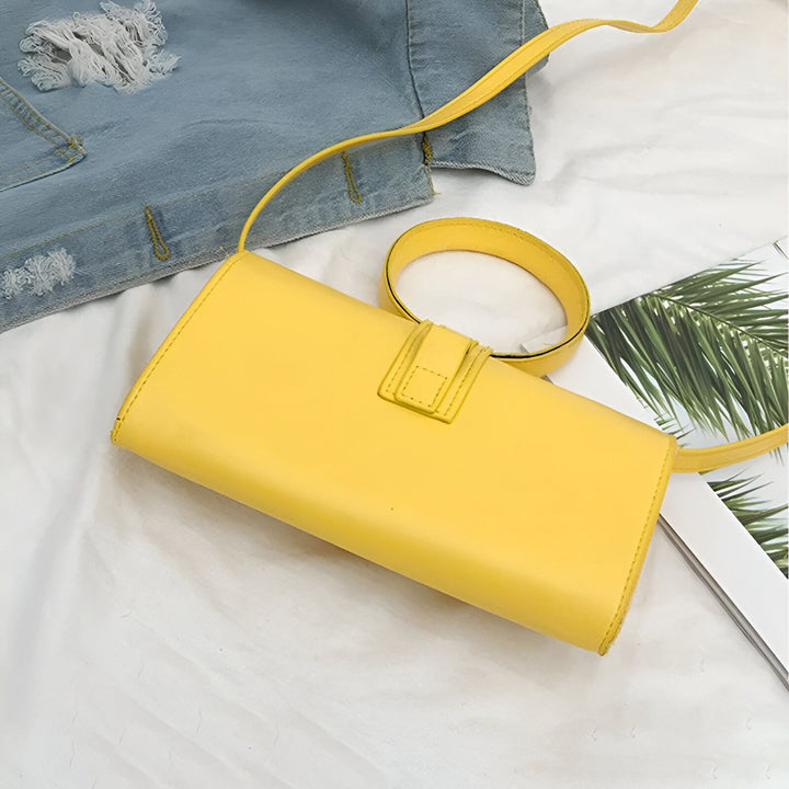 Sac bandoulière jaune en forme de cylindre sur un drap blanc près d'une veste en jean., 46193958748384,46193958813920,46193958846688,46193958879456,46193958912224,46193958944992