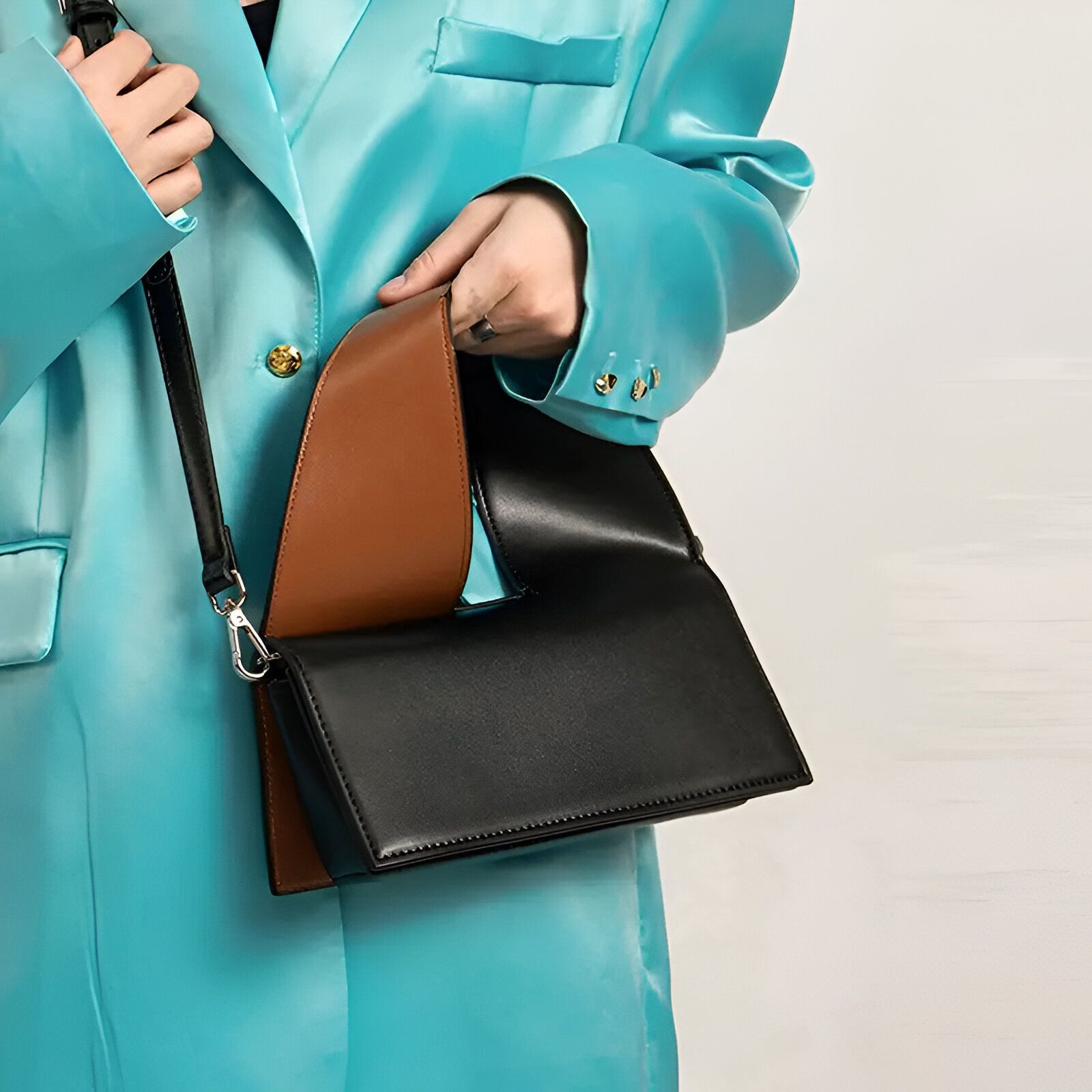 Une femme portant un blazer bleu turquoise et un sac à main noir et marron.