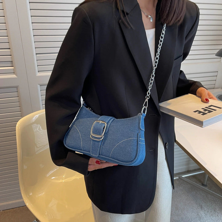 Sac baguette en jean bleu avec chaîne argentée, porté par une personne en blazer noir tenant un livre., 46193994399968,46193994432736