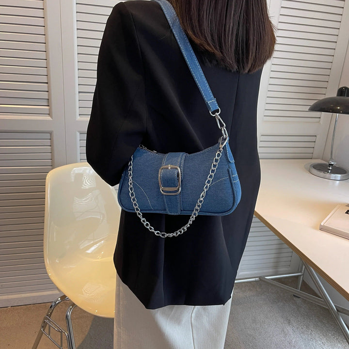 Sac baguette en jean bleu porté à l'épaule avec chaîne et boucle argentées., 46193994399968,46193994432736