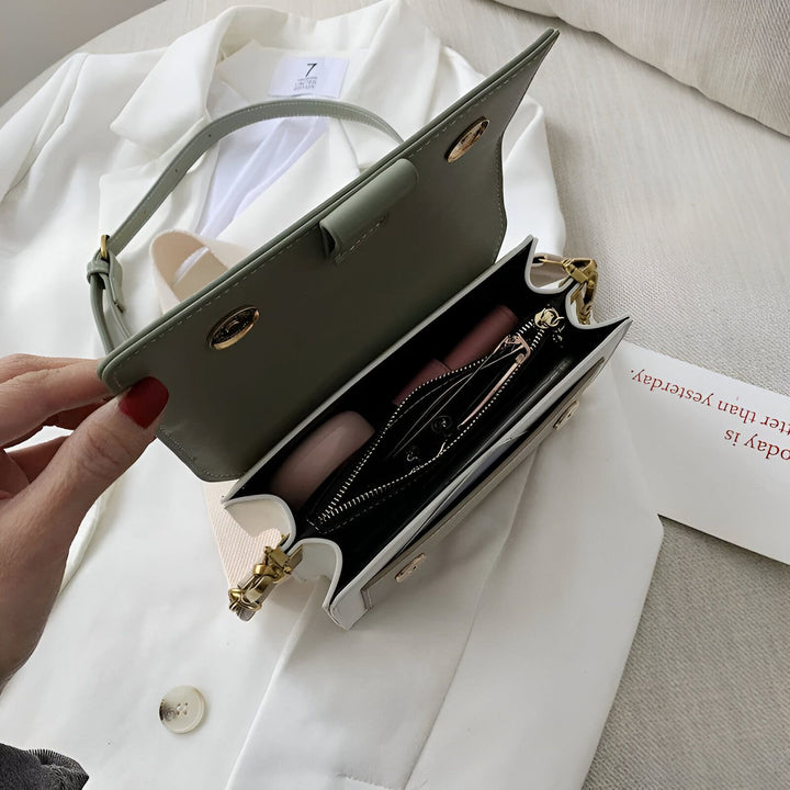 Petite sacoche vert pâle ouverte montrant l'intérieur avec du rouge à lèvres sur un blazer blanc., 46193877221600,46193877254368,46193877287136,46193877319904