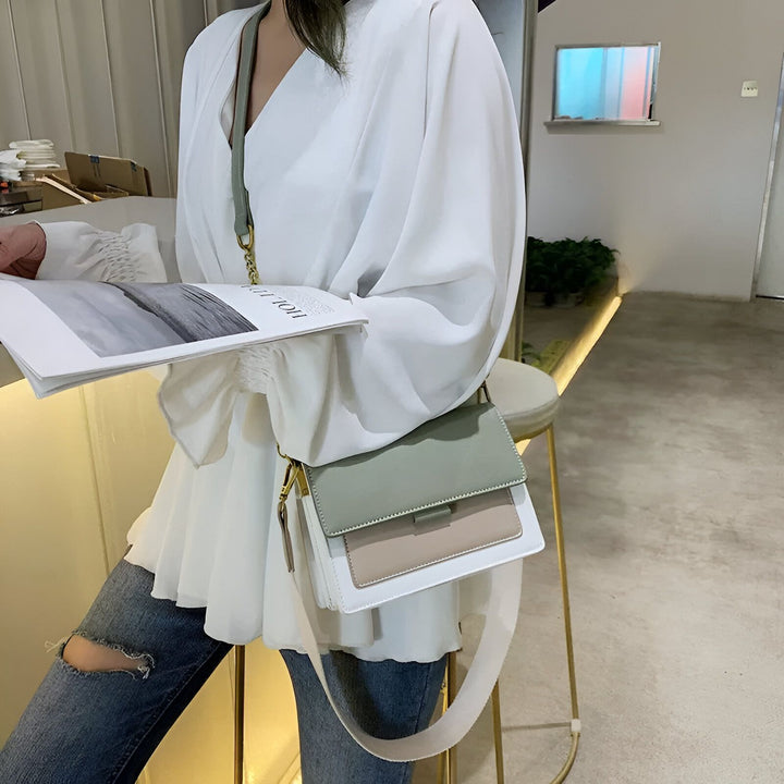 Femme avec magazine, portant un top blanc, un jean déchiré et un sac bandoulière tricolore., 46193877221600,46193877254368,46193877287136,46193877319904