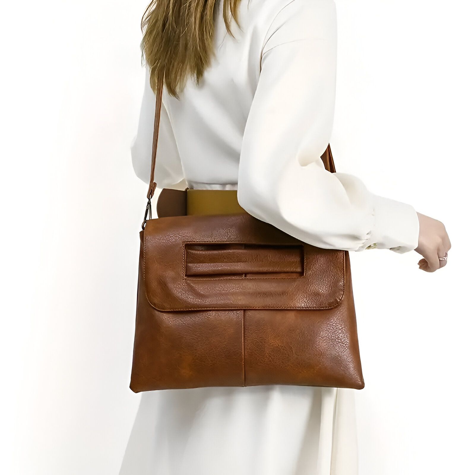 Une femme en chemise blanche porte un sac à main en cuir marron.