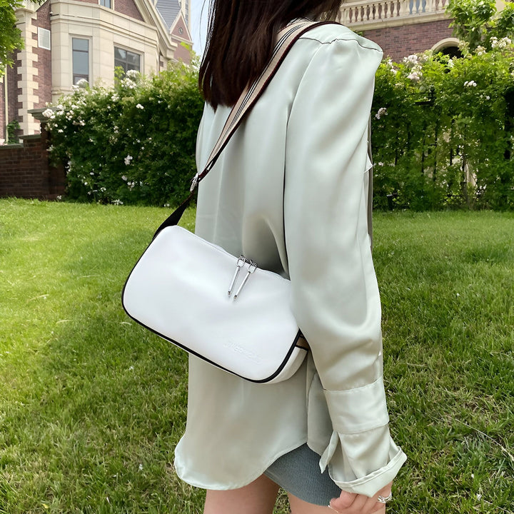 Personne de dos portant un sac bandoulière blanc et une chemise verte dans un jardin., 46266441433312,46266441466080,46266441498848