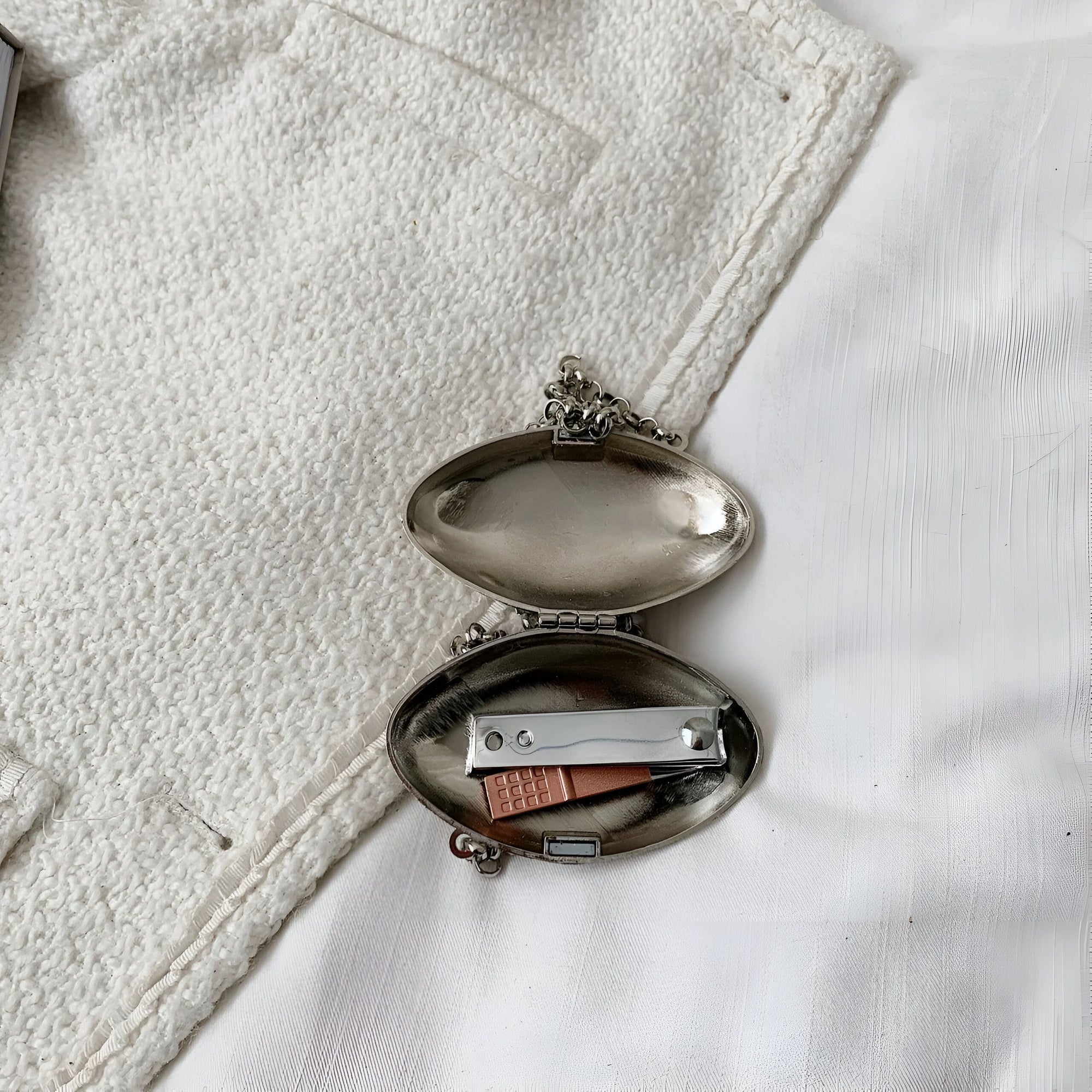 Un petit étui en métal argenté ouvert avec une lime à ongles et un coupe-ongles à l'intérieur.