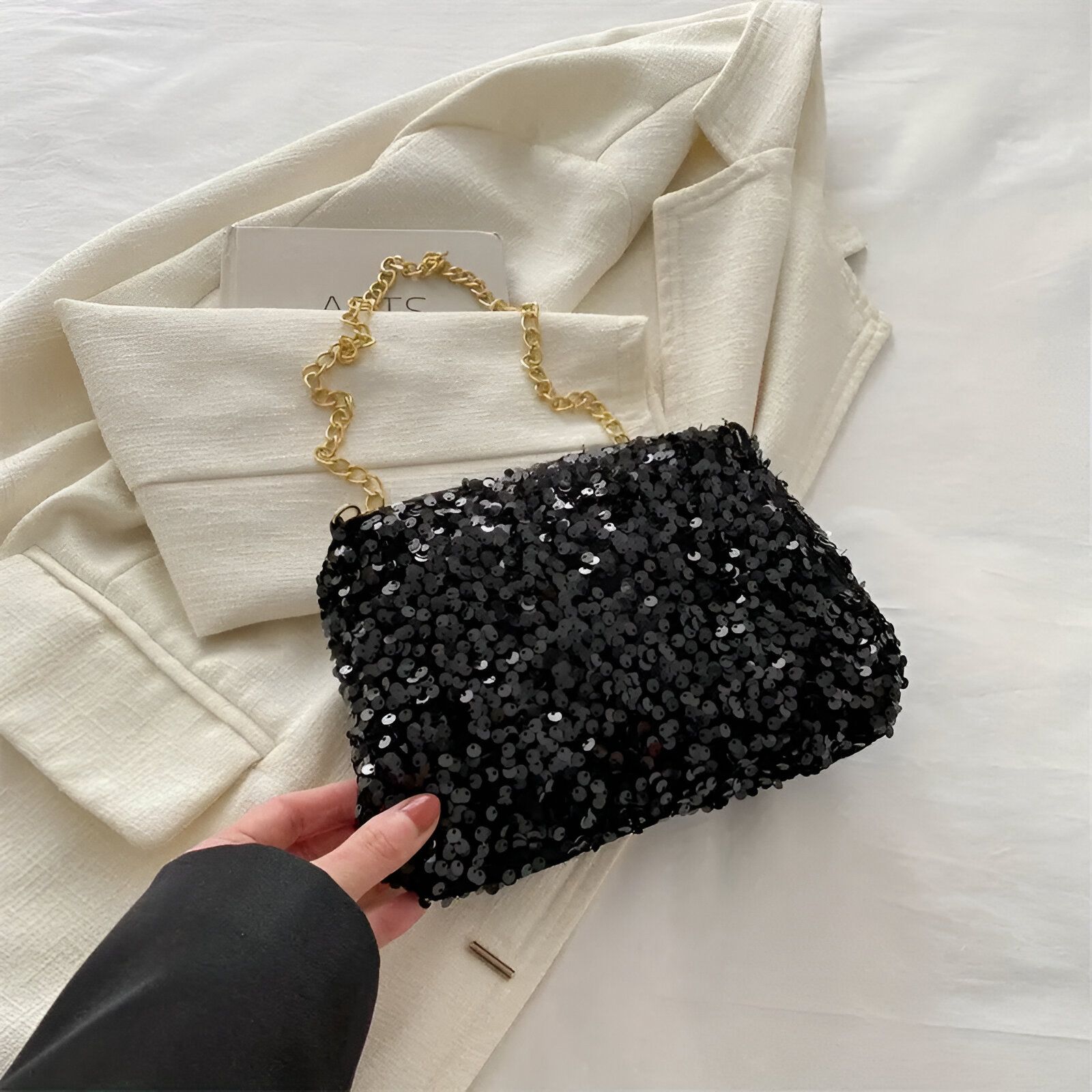 Un petit sac à main noir pailleté avec une chaîne dorée.