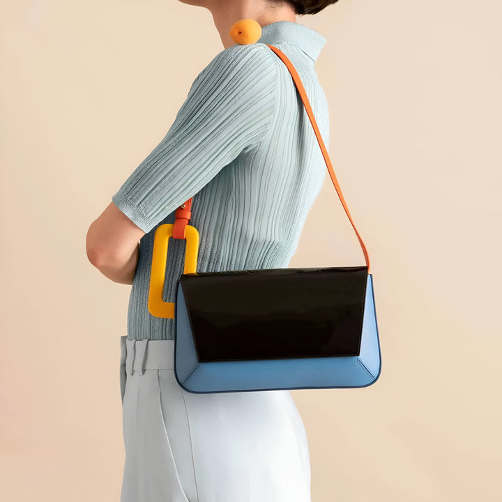 Femme portant un sac à main bleu et noir avec anse orange et accessoire jaune, un abricot sur l'épaule., 46193873715424,46193873748192,46193873780960,46193873813728,46193873846496