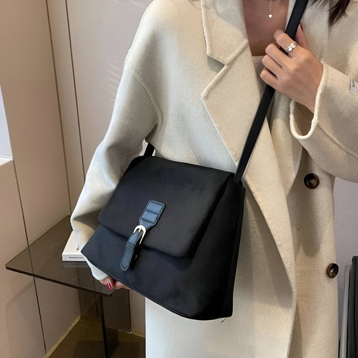 Femme avec manteau beige tenant un sac noir bandoulière à boucle., 46193887510752,46193887543520
