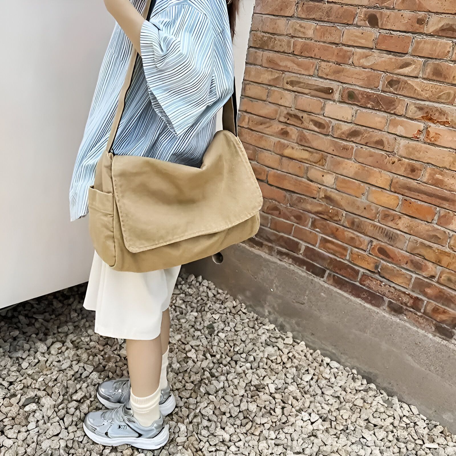 Une femme portant un sac à bandoulière en toile beige.