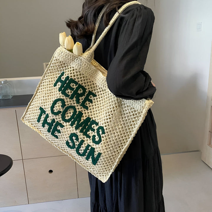 Femme avec sac cabas tressé "HERE COMES THE SUN" contenant des tulipes., 46193944723680,46193944756448