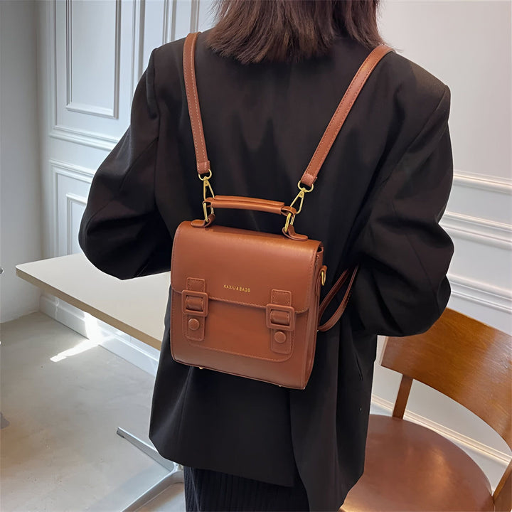 Sac à dos marron en cuir avec boucles porté par une personne de dos., 46194003312864,46194003345632,46194003378400,46194003411168