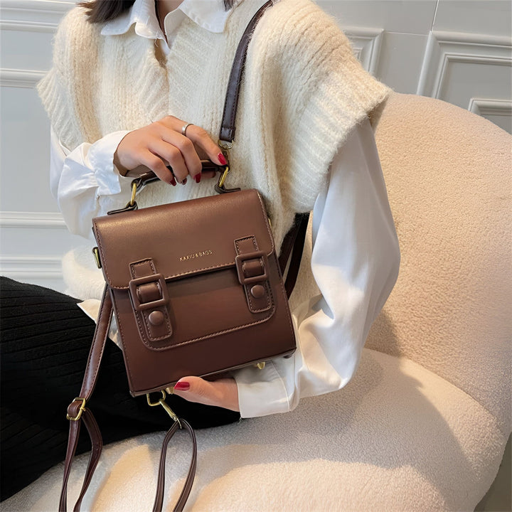 Petit sac à main marron avec poignée, bandoulière et boucles, porté par une femme., 46194003312864,46194003345632,46194003378400,46194003411168